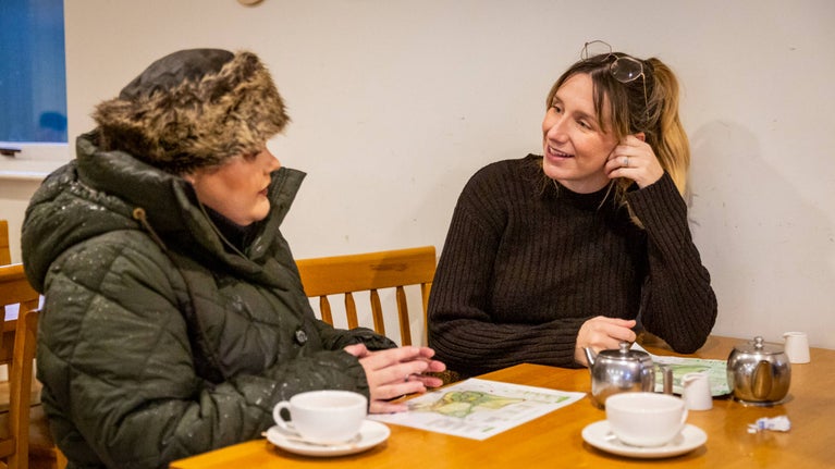 Two visitors chatting while enjoying coffee in the café
